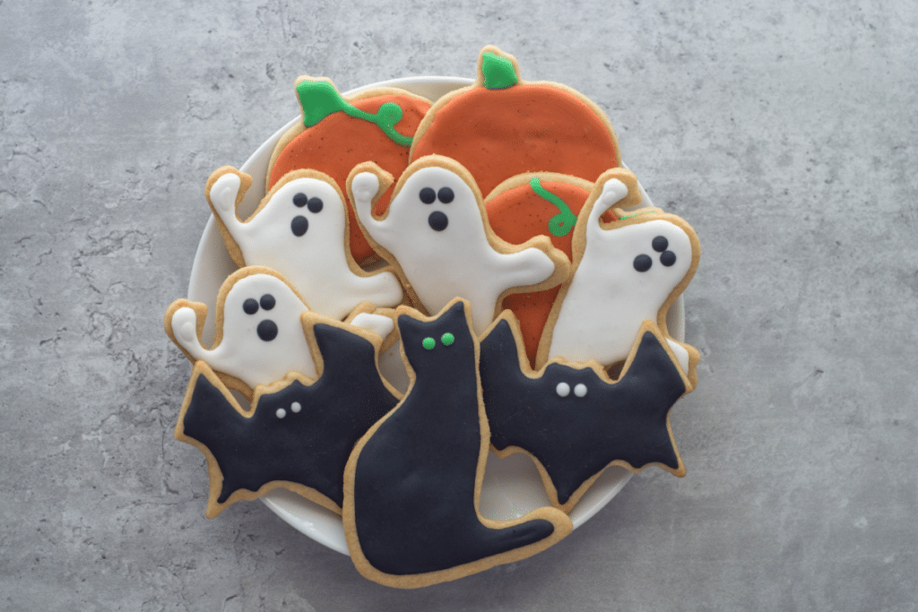 A plate of frosted Halloween cookies sits on a gray counter.